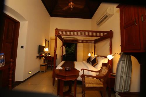 a bedroom with a bed and a table and a chair at THE HILLWAY HERITAGE in Trivandrum