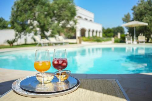 dos copas de vino sentadas en una bandeja junto a una piscina en Villa de Lua en Leporano