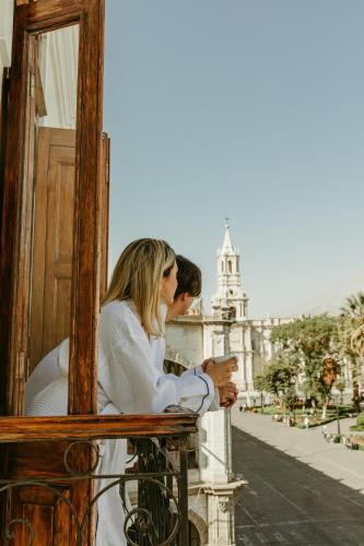 a man and a woman sitting on a balcony looking at a building at Plaza Central in Arequipa