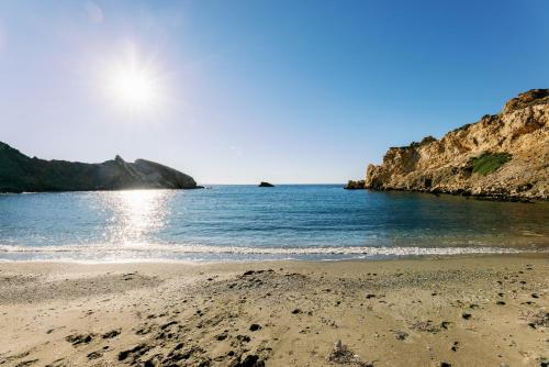 a beach with the sun shining on the water at Mikra Bay Vineyard Guesthouses in Naxos Chora