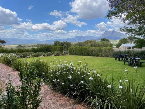 a garden with flowers and tables and mountains in the background at Bona Vista Self-Catering Accommodation in Klapmuts