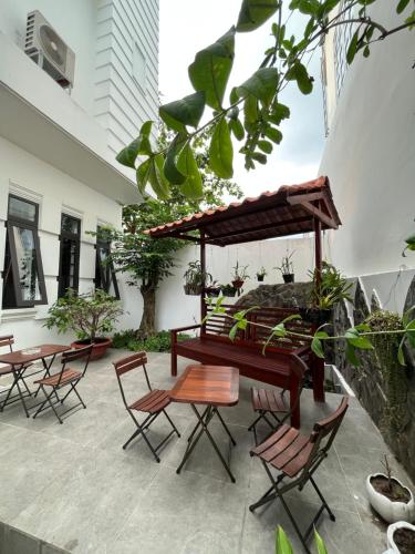 eine Terrasse mit einer Bank, Tischen und Stühlen in der Unterkunft Queenie House in Cần Thơ