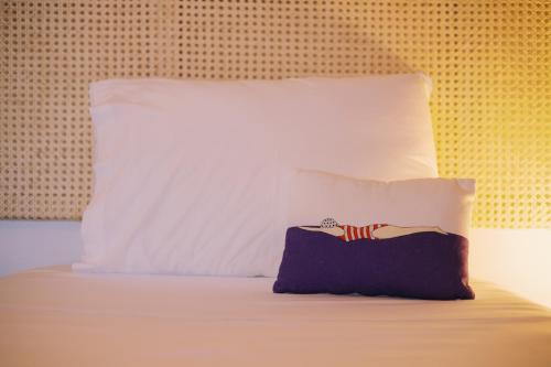 a bed with a pillow and a large white pillows at Mikra Bay Vineyard Guesthouses in Naxos Chora