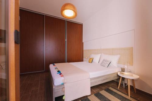 a bedroom with a white bed and a wooden cabinet at Mikra Bay Vineyard Guesthouses in Naxos Chora