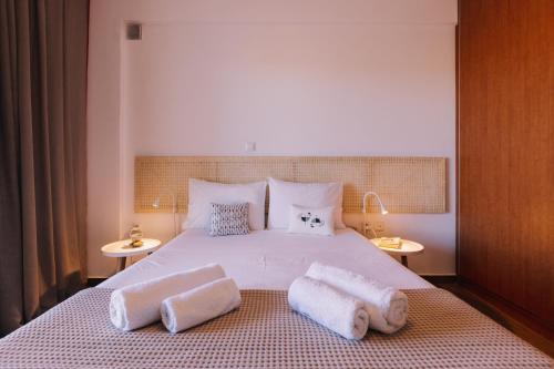 a bedroom with a large white bed with towels on it at Mikra Bay Vineyard Guesthouses in Naxos Chora