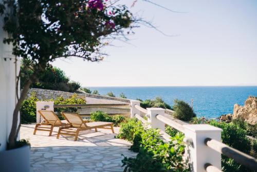 a patio with chairs and the ocean in the background at Mikra Bay Vineyard Guesthouses in Naxos Chora