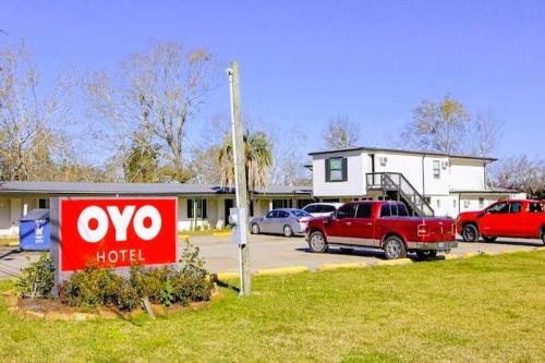 um sinal de hotel num parque de estacionamento em frente a uma casa em OYO Hotel Sulphur LA Hwy 90 West em Sulphur