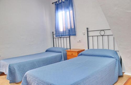 dwa łóżka w pokoju z niebieską pościelą i oknem w obiekcie Apartamento Velarde II w mieście Conil de la Frontera