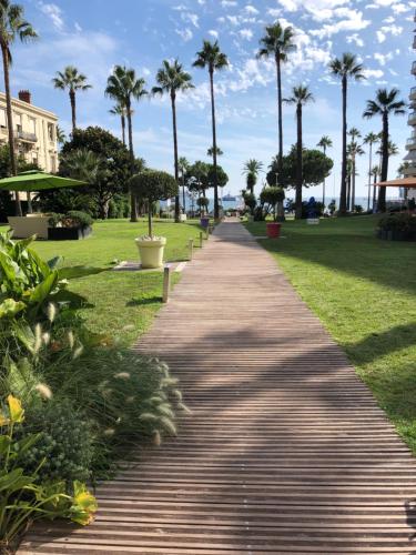 une passerelle dans un parc planté de palmiers dans l'établissement Studio Cannes Grand Hôtel Eider, à Cannes