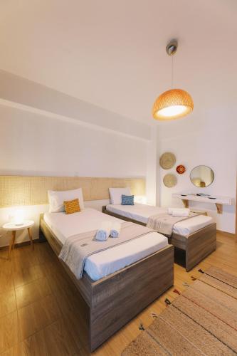 a bedroom with two beds and a table and a lamp at Mikra Bay Vineyard Guesthouses in Naxos Chora