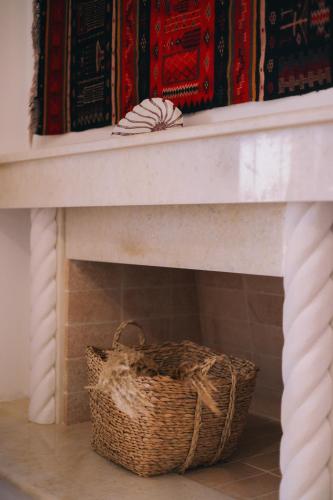 a basket sitting next to a fireplace with blankets at Mikra Bay Vineyard Guesthouses in Naxos Chora