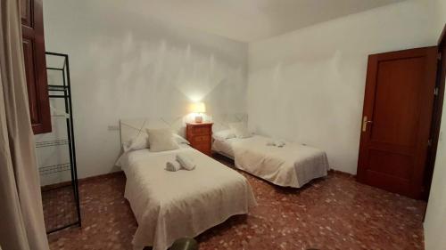 a bedroom with two beds and a light on the wall at Casa Rural Doña Catalina in Jimena de la Frontera