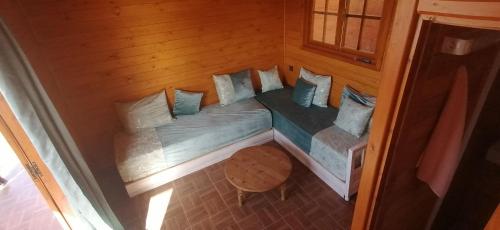 a small bed in a wooden room with pillows at Ferme Sacrée Nature in Ben Slimane