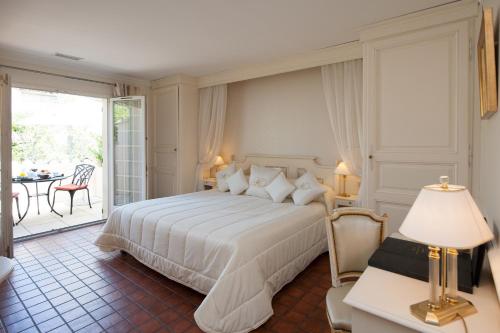ル・ポンテにあるオーベルジュ ド カサーニュ＆スパのベッドルーム(大きな白いベッド1台付)、パティオが備わります。