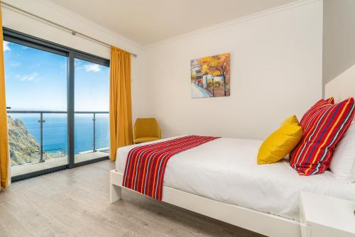 a bedroom with a bed with a view of the ocean at OurMadeira - Sunset Cliff Villas, contemporary in Fajã da Ovelha