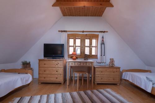 a bedroom with two beds and a desk with a television at Traditional cozy cottage BOCANKA in Nižná Boca