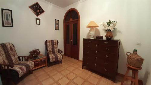 a living room with a dresser and a chair and a lamp at Casa Rural Doña Catalina in Jimena de la Frontera