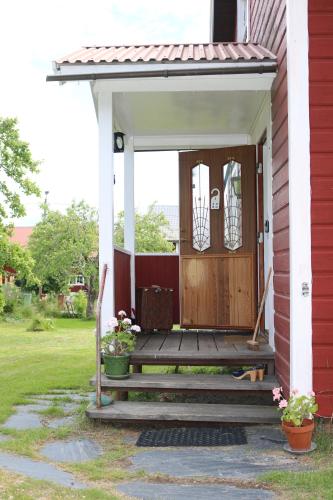 weranda czerwonego domu z drewnianymi drzwiami w obiekcie Familjevänligt hus med stor trädgård w mieście Vallsta