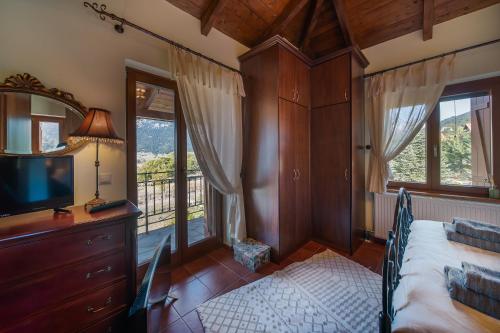 a bedroom with a bed and a television and a balcony at Livadi cozy villa in Arachova