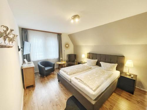 a hotel room with a large bed and a chair at Pension Trautheim - Am Stadtpark in Bad Harzburg