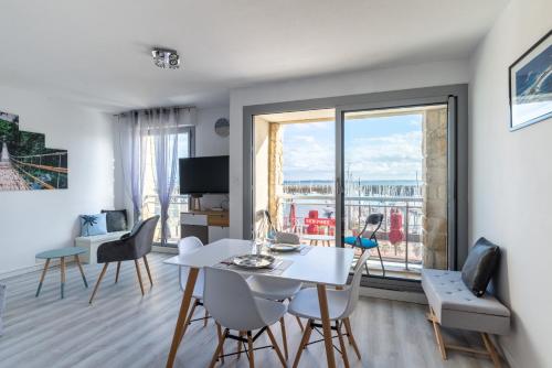 - un salon avec une table, des chaises et une grande fenêtre dans l'établissement Marée Tropicale - vue mer, à Saint-Cast-le-Guildo