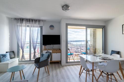 salon ze stołem, krzesłami i telewizorem w obiekcie Marée Tropicale - vue mer w mieście Saint-Cast-le-Guildo