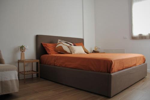 a bed with orange and white pillows on it at New apartment close to the Cinque Terre in La Spezia
