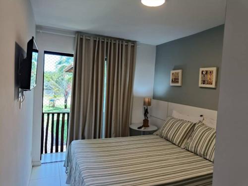 a bedroom with a bed and a balcony with a television at Apartamento Na Praia De Itacimirim in Itacimirim