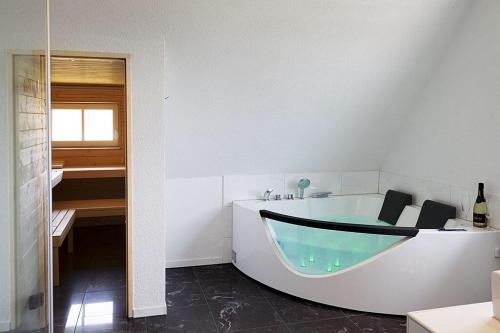 La salle de bains blanche est pourvue d'une baignoire et d'un lavabo. dans l'établissement Schwarzwaldhaus24 - Ferienhaus mit Sauna, Whirlpool und Kamin, à Gemeinde Aichhalden