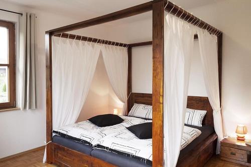 um quarto com uma cama de dossel e cortinas brancas em Schwarzwaldhaus24 - Ferienhaus mit Sauna, Whirlpool und Kamin em Gemeinde Aichhalden