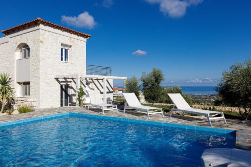 una piscina con 2 sillas y una casa en Komfortvilla sensationeller Meerblick priv. Pool en Agia Triada