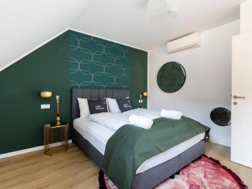 Un dormitorio con una cama con una pared de acento verde en limehome Klagenfurt Goessgasse, en Klagenfurt