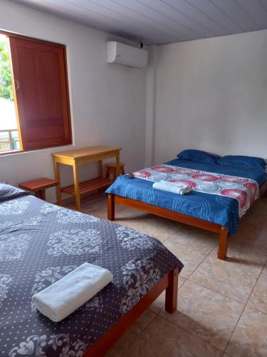 1 dormitorio con 2 camas, mesa y ventana en Hotel CHAFO, en Leticia