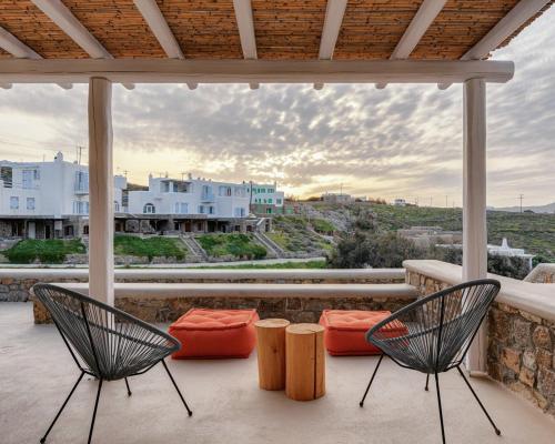 two chairs on a balcony with a view of a city at Koumi Homes Mykonos in Elia
