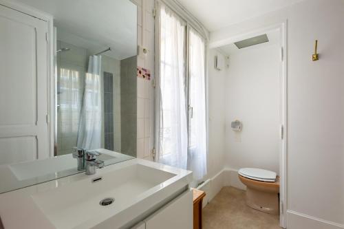 La salle de bains blanche est pourvue d'un lavabo et de toilettes. dans l'établissement Amandus, à Rouen