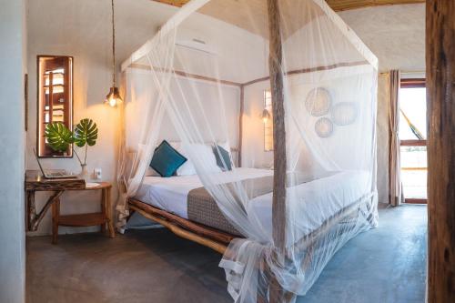 a bedroom with a canopy bed with mosquito nets at Beekite Wind Village in Luis Correia