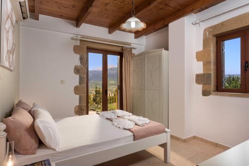 a white bedroom with a bed and a window at Villa Gianna by PosarelliVillas in Fílippos