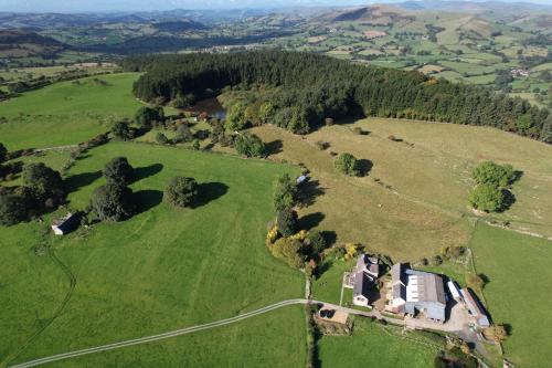 an aerial view of a house in a field at The Granary at Pentregaer Ucha, tennis court & lake. in Oswestry
