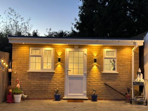 mały ceglany dom z białymi drzwiami i światłami w obiekcie Touchwood w mieście Isleworth
