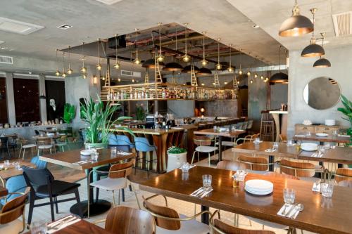 um restaurante com mesas e cadeiras de madeira e um bar em Brown Brut Seafront Hotel, a member of Brown Hotels em Tel Aviv