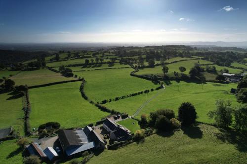 an aerial view of a field with houses and trees at The Nook at Pentregaer Ucha, with tennis court & lake. in Oswestry