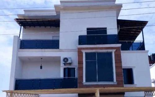 a white house with blue windows and a balcony at Credence Resorts Aco in Ligwai