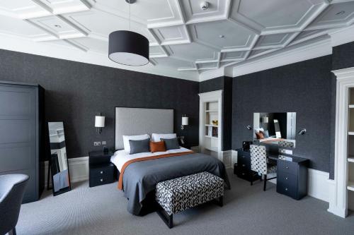 um quarto com uma cama, uma secretária e uma cadeira em The Chester Hotel em Aberdeen