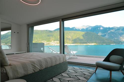 a bedroom with a bed and a chair and a large window at One Only Lake View Penthouse no01 in Melide