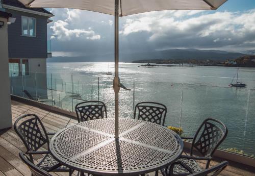 un tavolo e sedie con ombrellone su un balcone di The Ridge a Menai Bridge