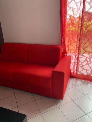 a red couch sitting in front of a window at La Résidence Les Grands Vignobles in Libourne