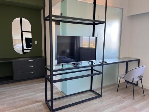 estante de cristal con TV y silla en una habitación en Nuevo Hotel Ancasti en San Fernando del Valle de Catamarca
