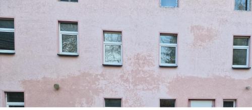 ein rosafarbenes Gebäude mit vier Fenstern darauf in der Unterkunft SleepArt-Naumburg 