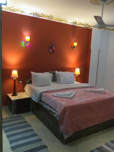 a bedroom with a large bed with a red wall at The Brown House in Luxor