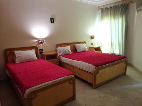 a bedroom with two beds with red sheets and a window at Golden Rose Hotel in Hurghada